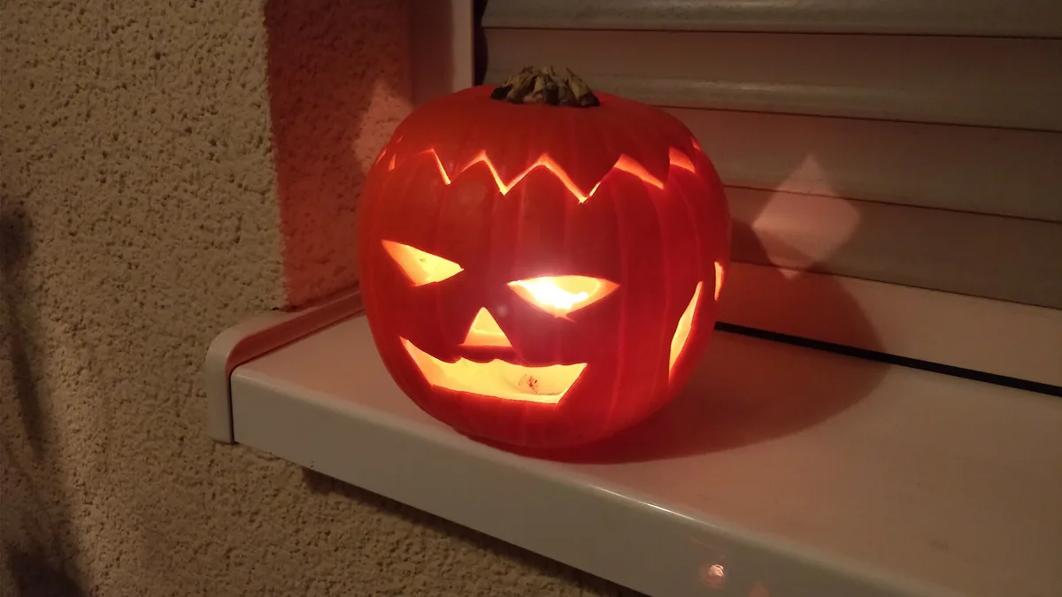Geschnitzter Halloween-Kürbis mit Kerze auf einer Fensterbank bei Nacht